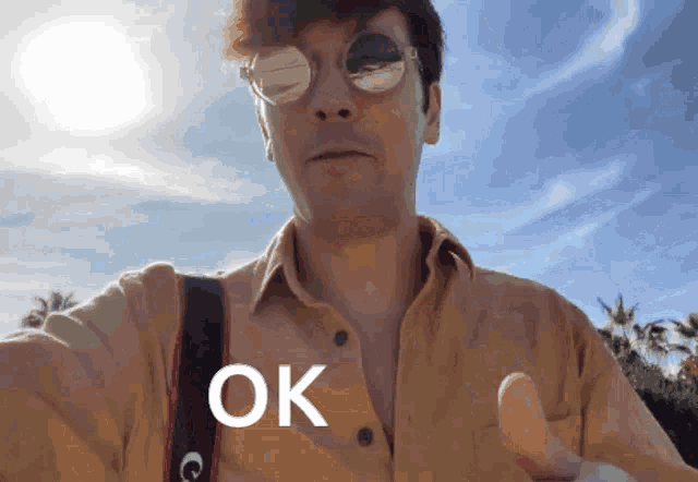 a man wearing sunglasses giving a thumbs up with the word ok on his chest