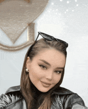 a woman wearing sunglasses and a black leather jacket looks at the camera