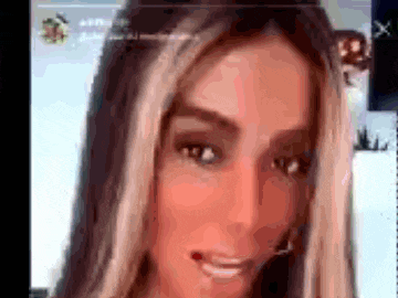 a close up of a woman 's face with long hair and a smile on her face .