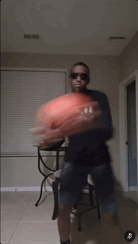 a man wearing sunglasses holds a basketball in a room