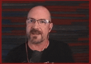 a man wearing glasses and a shirt that says cas is pointing