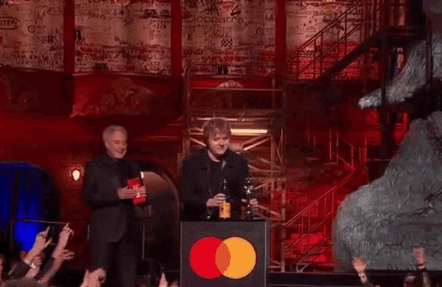 a man is holding a trophy in front of a mastercard sign