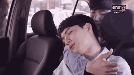 a man is hugging another man in a car .