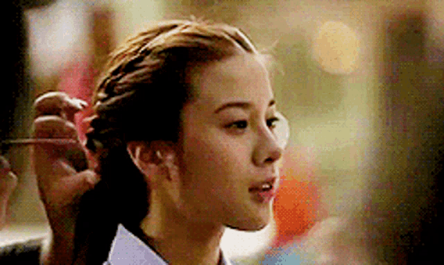 a close up of a woman 's face with a person holding her hair .