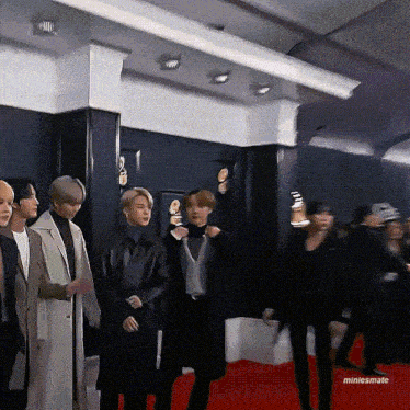 a group of people are standing on a red carpet with the name miniesmate on the bottom right