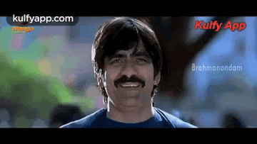 a man with a mustache and a blue shirt is smiling and looking at the camera .