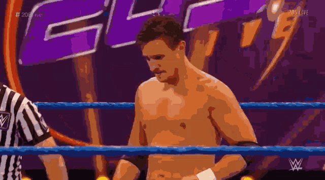 a shirtless wrestler stands in a wrestling ring with a referee and a wwe logo in the background