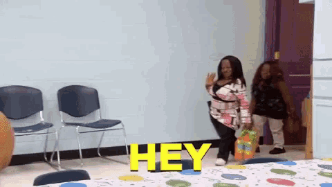 a woman standing in a room with the word hey written on the wall