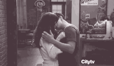 a man and a woman are hugging and kissing in front of a restaurant .