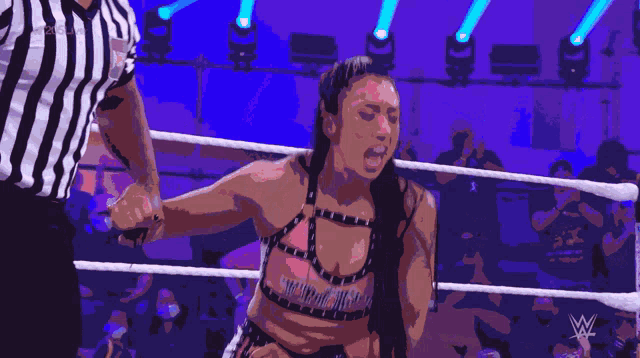 a woman in a wrestling ring is being escorted by a referee with a wwe logo in the background