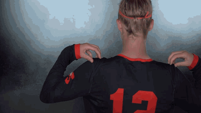 a woman wearing a black jersey with the number 12 on the back