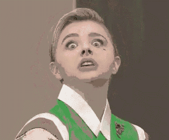 a close up of a woman 's face with a green shirt and white collar looking up .