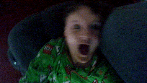 a child yawning in a car seat with his mouth wide open