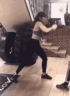 a woman is boxing in a gym in front of a large tire .