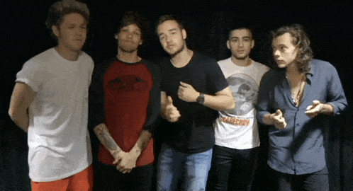 a group of men are posing for a picture and one of them is wearing a shirt that says direction