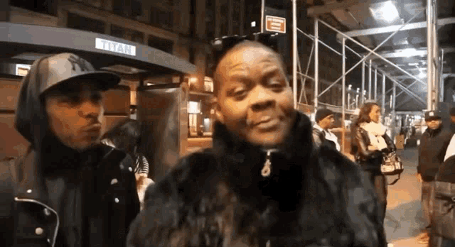 a man wearing a ny hat is standing next to a woman in a fur coat