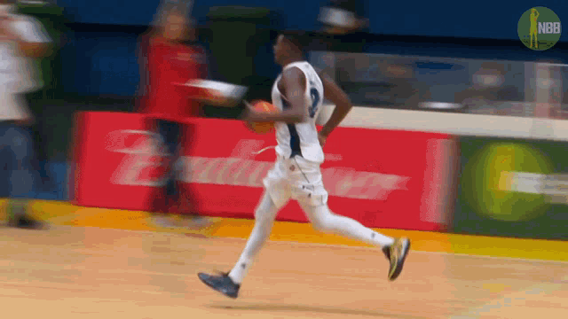 a basketball player is running on a court with a budweiser advertisement in the background