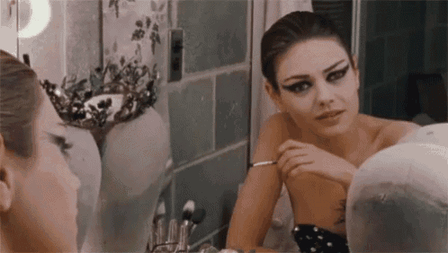 a woman is looking at herself in a mirror .
