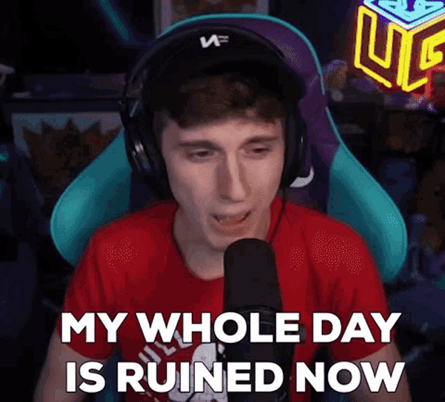 a man wearing headphones is sitting in front of a microphone and saying `` my whole day is ruined now ''