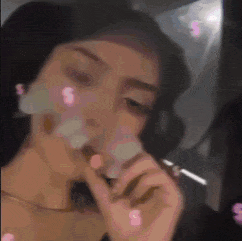 a woman is smoking a cigarette with smoke coming out of her mouth .