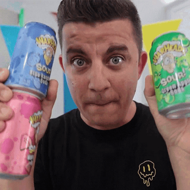 a man in a black shirt holds up two cans of sour head