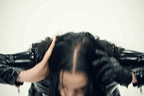 a woman wearing black gloves is holding her hair