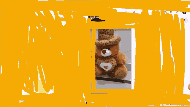 a teddy bear wearing a top hat is behind a yellow wall