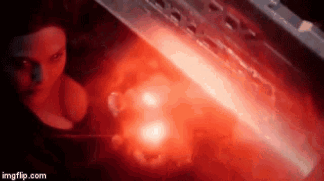 a woman is standing in a dark room with a red light coming out of the ceiling .