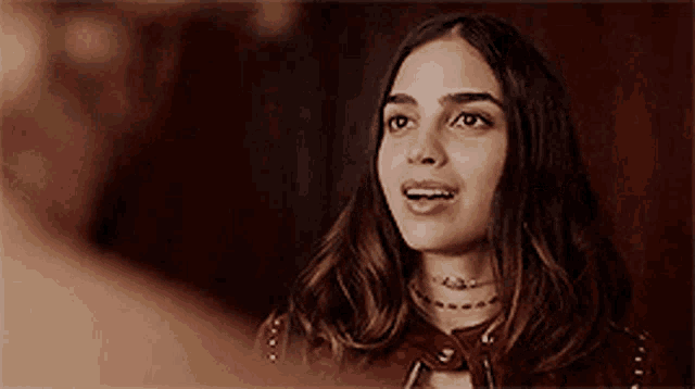 a woman in a red leather jacket is smiling and looking at another woman .