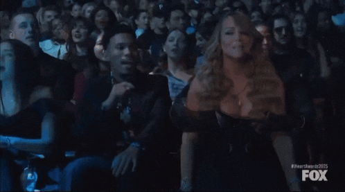 a woman in a black dress is dancing in a crowd at a fox awards show