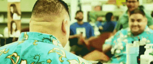 a man in a blue shirt is looking at himself in a mirror