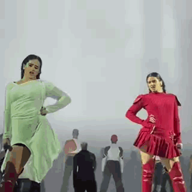 a couple of women are dancing on a stage in front of a crowd .