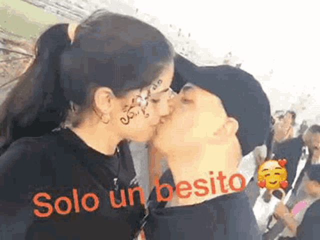 a man and woman are kissing in front of a crowd of people .