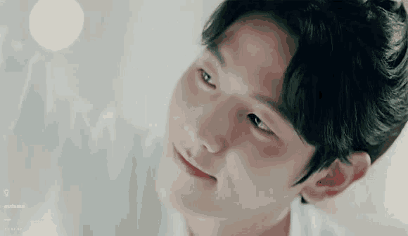 a close up of a young man 's face with a smile on his face and looking up .