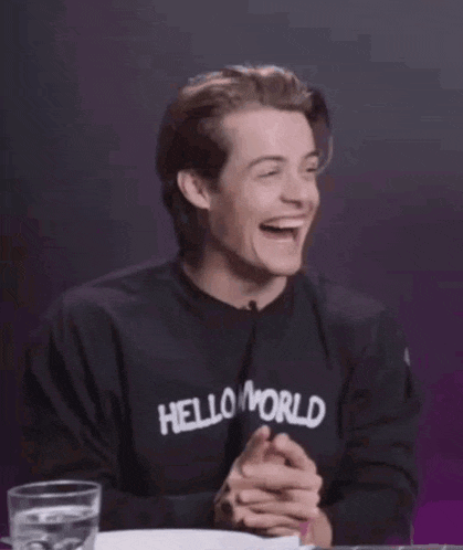 a man wearing a black shirt with the word world on it is laughing with his hands outstretched .