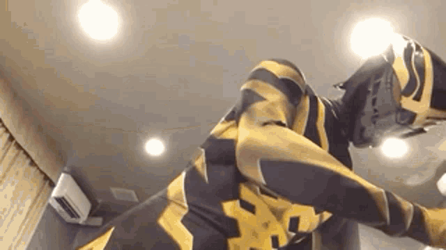 a person in a yellow and black striped superhero costume is laying on the floor .