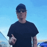 a man wearing sunglasses and a hat is giving a thumbs up .