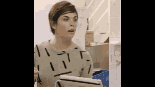 a woman is holding a tablet in her hand and making a funny face .