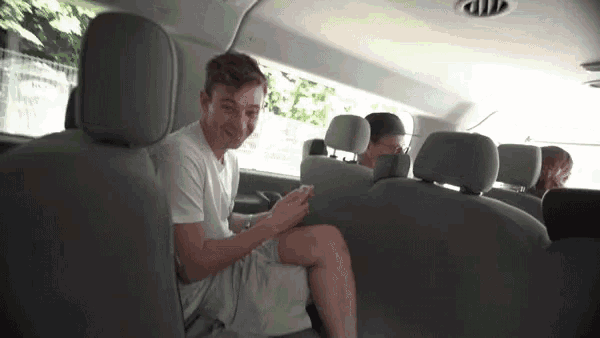 a young man is sitting in the back seat of a van looking at his cell phone .