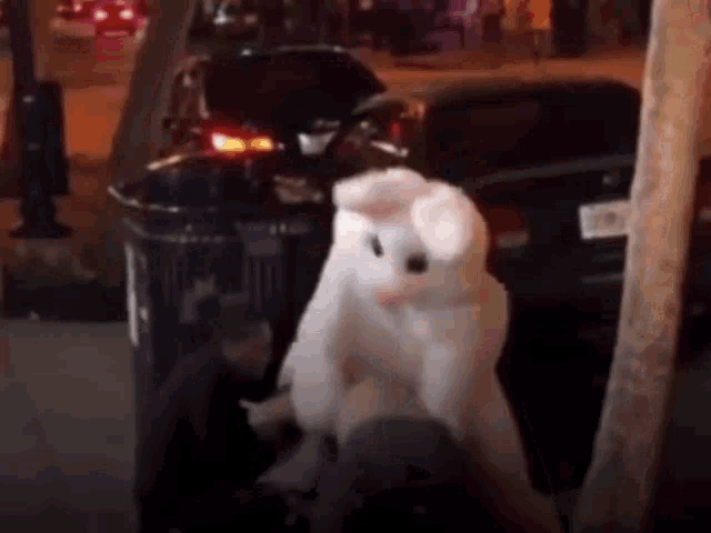a person in a bunny costume is standing next to a trash can .