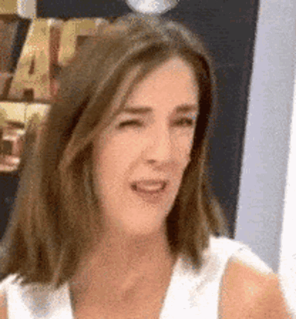 a woman in a white tank top is making a funny face