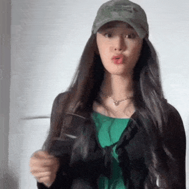 a woman wearing a hat and a green shirt is making a face .