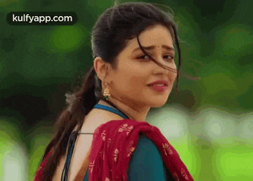 a close up of a woman wearing a blue blouse and a red dupatta .