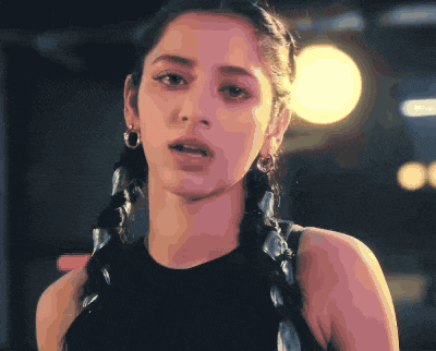 a close up of a woman 's face with braids and earrings