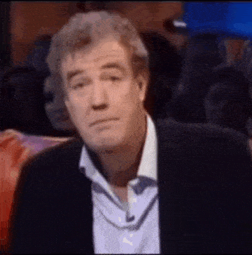 a man in a suit and tie is making a funny face in front of a crowd of people .