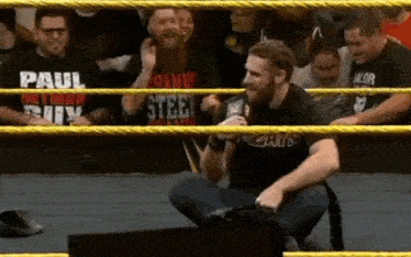 a man in a wrestling ring wearing a black shirt that says paul