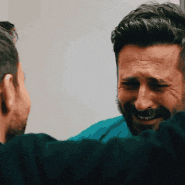 a man with a beard is laughing while another man looks on