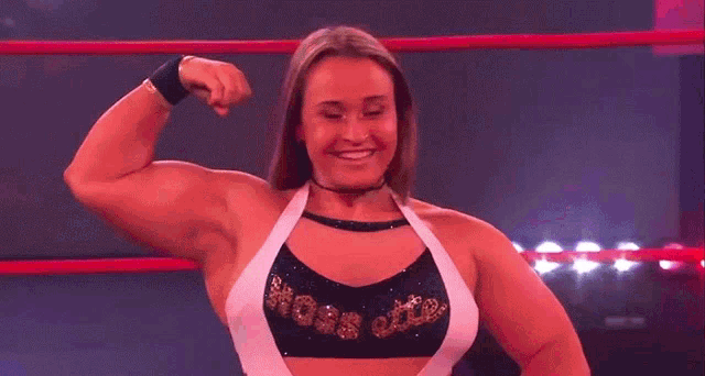 a female wrestler is flexing her muscles in a wrestling ring while wearing a top that says hoss