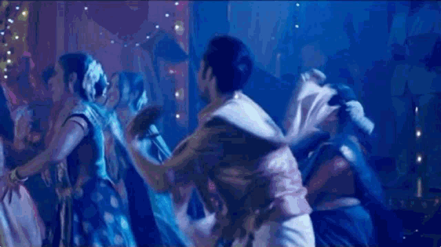 a blurry picture of a group of people dancing in a dark room .