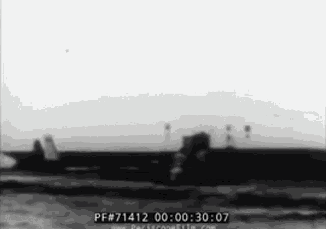 a black and white photo of a plane flying over the water
